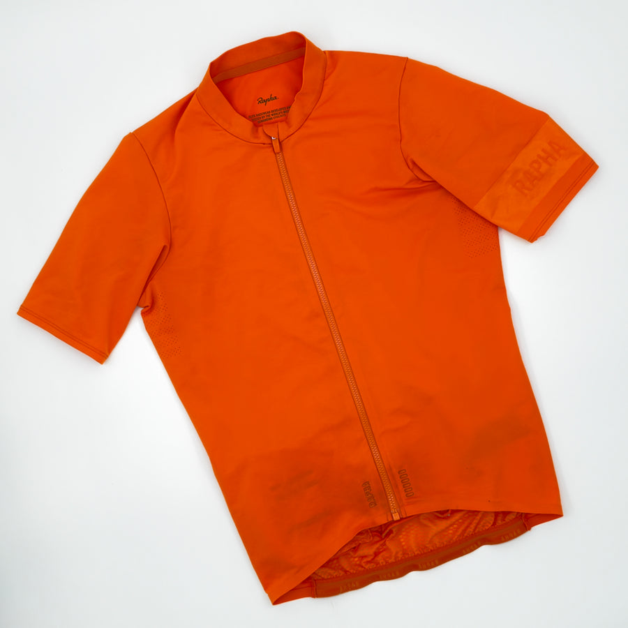 Rapha Men's Pro Team Midweight Jersey in orange, angled front view with tonal RAPHA cuff band