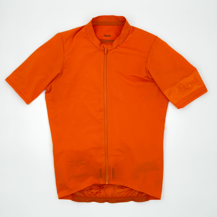Rapha Men's Pro Team Midweight Jersey in orange, angled front view with tonal RAPHA cuff band (alternate view)