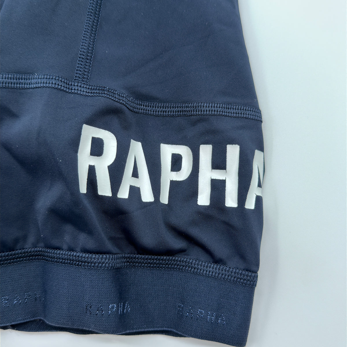Rapha Pro Team Training Bib Shorts leg hem detail showing white RAPHA print and silicone gripper band