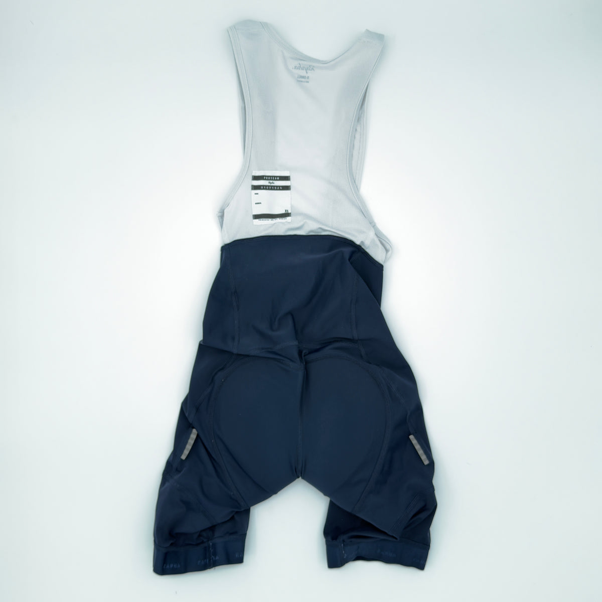 Rapha Pro Team Training Bib Shorts rear view showing white mesh bib upper and reflective tabs to the leg hems