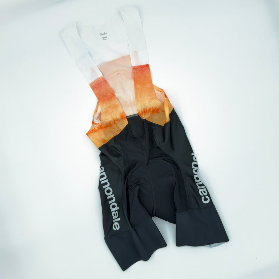 Rapha x Cannondale Pro Team Bib Shorts angled front showing white-to-orange bib upper and cannondale leg print