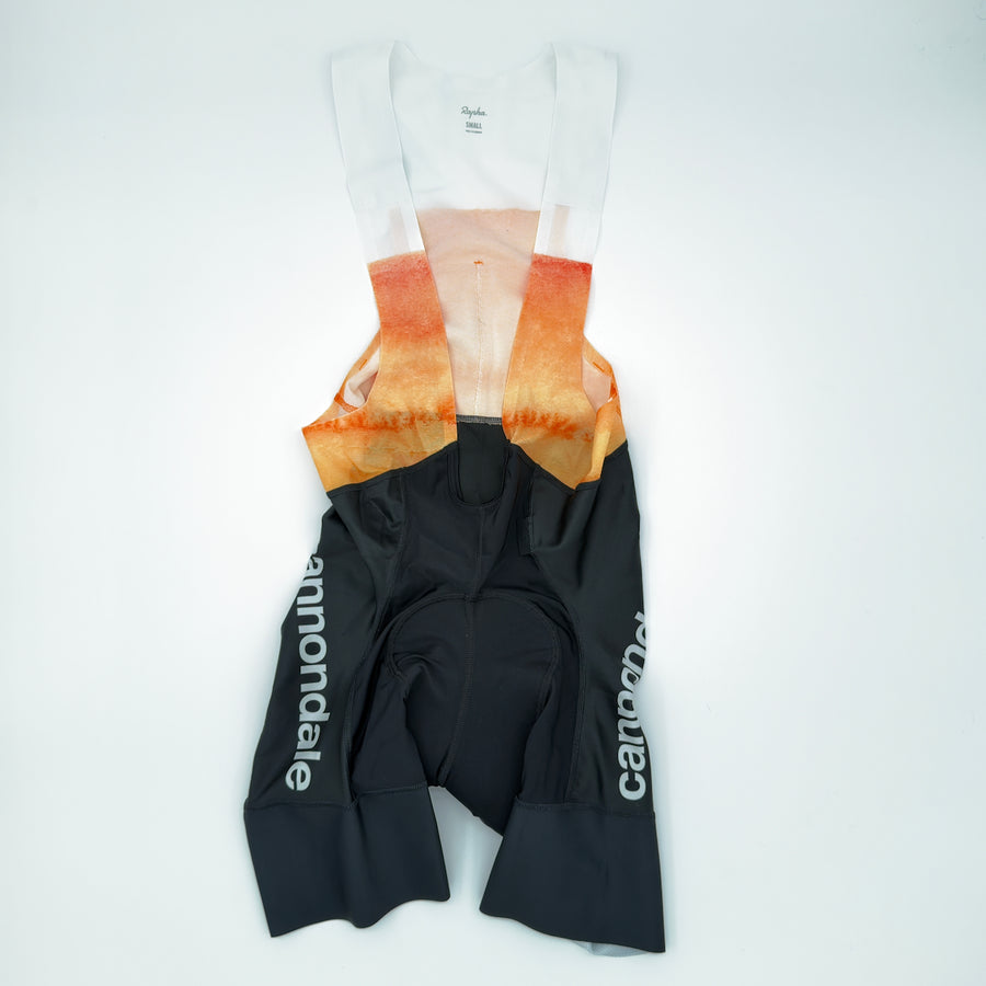 Rapha x Cannondale Pro Team Bib Shorts angled front showing white-to-orange bib upper and cannondale leg print (alternate view)