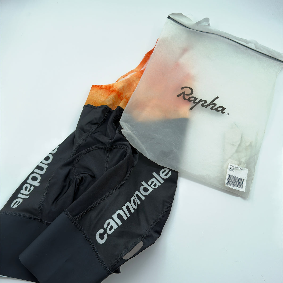 Rapha x Cannondale Pro Team Bib Shorts leg hem with reflective tab, shown beside the original Rapha team packaging labelled Race Bibshorts