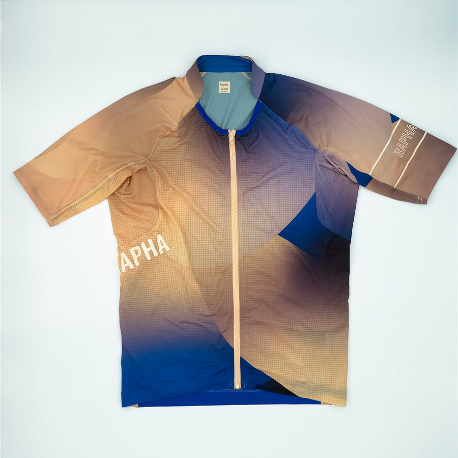 Rapha Pro Team Lightweight Jersey Surface Print angled front showing sand to cobalt gradient and diagonal RAPHA (alternate view)