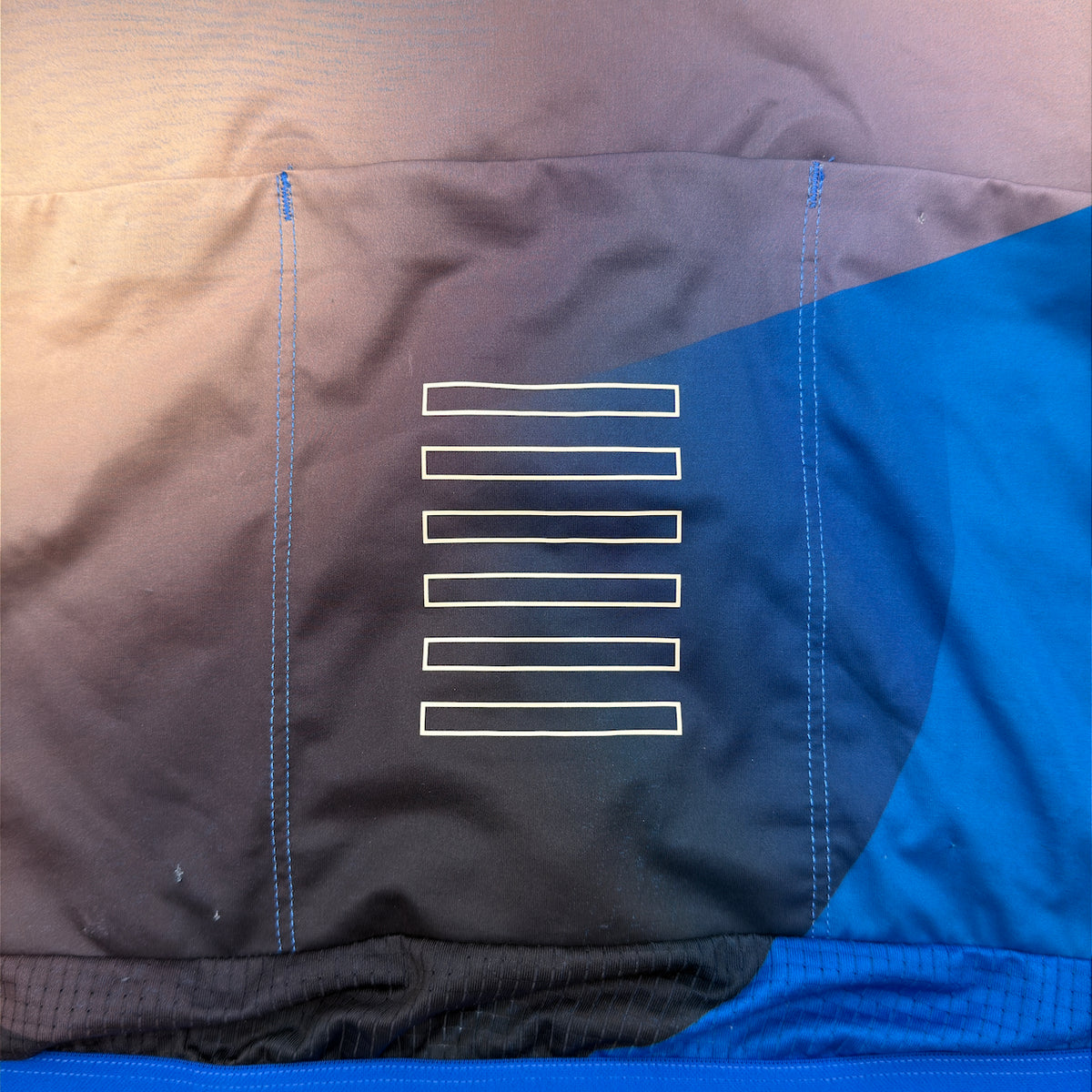 Rapha Pro Team Lightweight Jersey rear pocket close-up showing reflective bar print and pin holes from race numbers