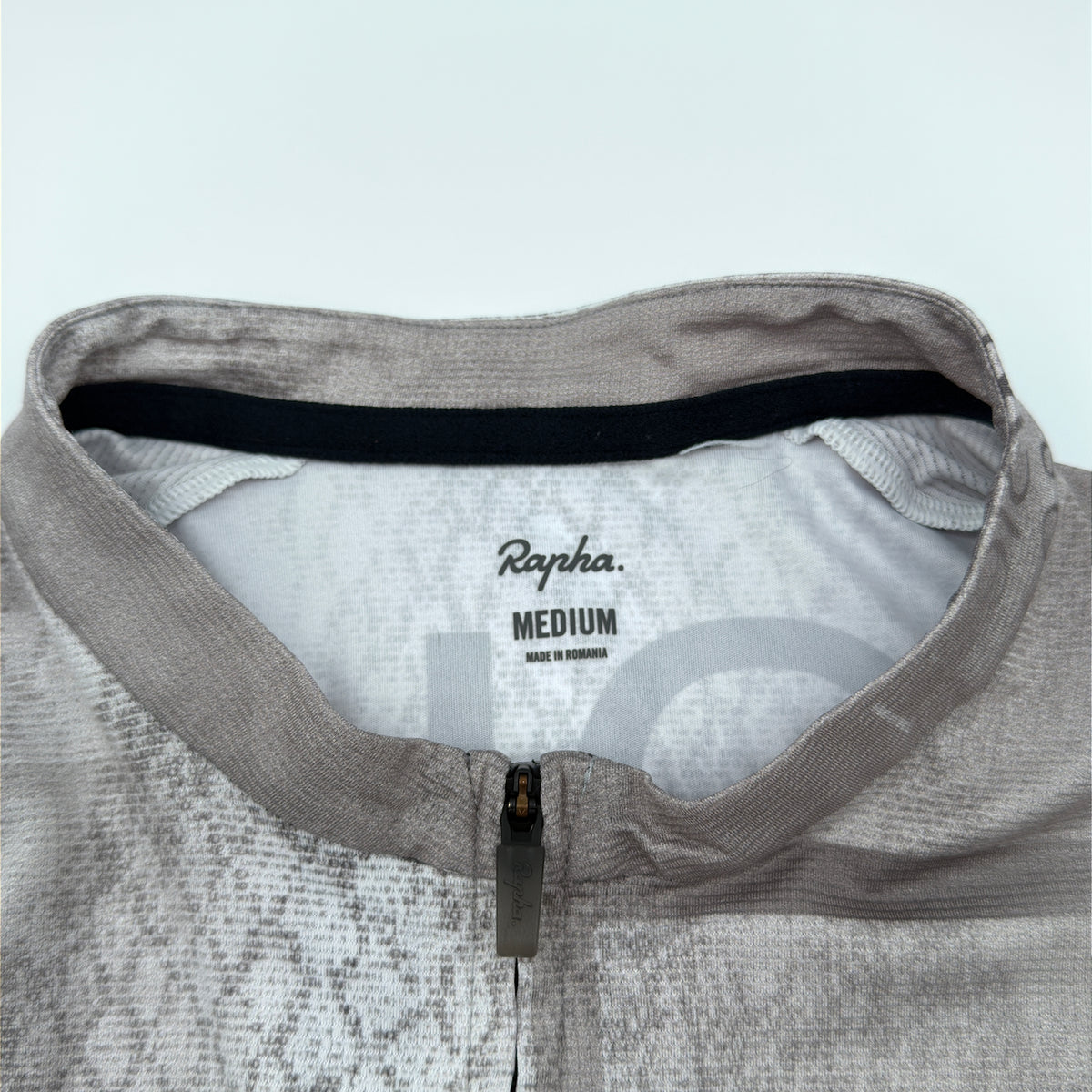 Rapha size label reading Medium, made in Romania, at the collar with waffle-textured knit visible