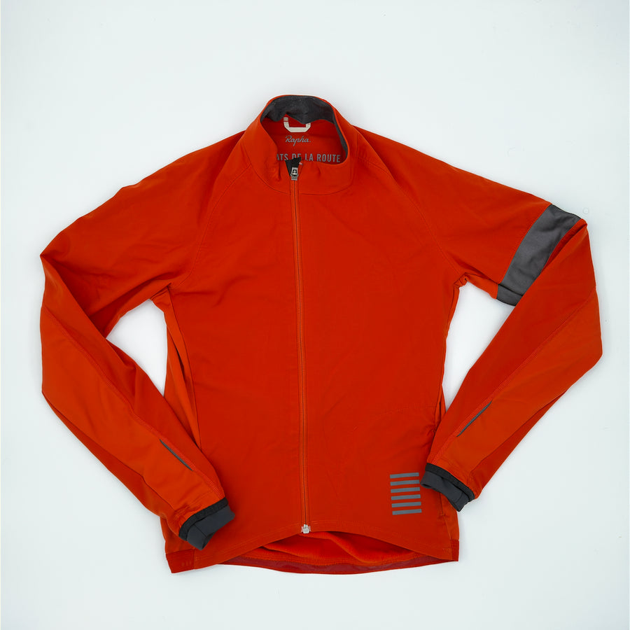 Rapha Pro Team Jacket angled front showing rust softshell, offset zip and charcoal armband (alternate view)
