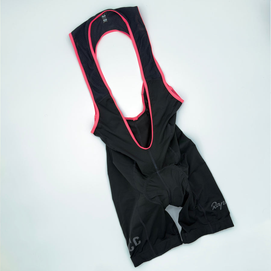 Rapha RCC Classic Bib Shorts II angled front showing black fabric with pink strap binding